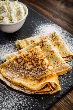 Crepes with cream on wooden table