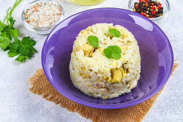 White steamed rice with slices of fried chicken fillet in a bowl on a concrete table.