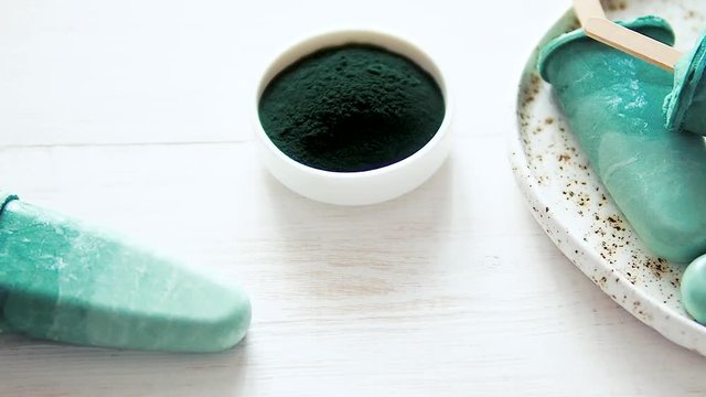 Superfood spirulina popsicles on white wooden tabletop. Ideas and recipes for healthy breakfast, summer vegetarian snack or vegan dessert. Popsicle with spirulina powder and coconut milk.