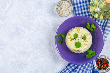 White steamed rice with slices of fried chicken fillet in a bowl on a concrete table. Top view.