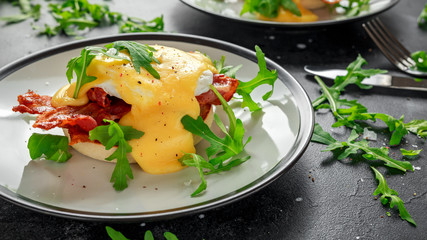 Eggs Benedict on english muffin with crispy bacon, wild rocket salad and hollandaise sauce.