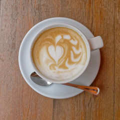hot caffe latte cup with spoon on brown wood background