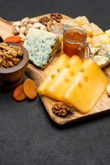 various types of cheese - brie, camembert, roquefort and cheddar on wooden board