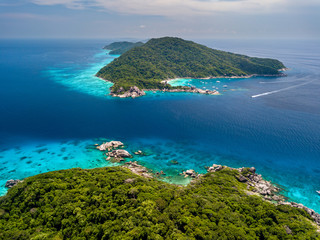 Aerial drone view of green tropical islands next to clear waters and a huge coral reef system