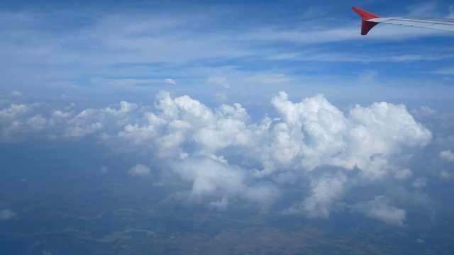4K footage. traveling by air. aerial view through an airplane window. wing airplane and beautiful white clouds in blue sky for background
