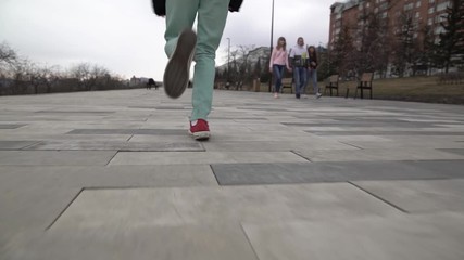 A teenage girl is running down the street. Red sneakers close-up.