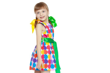 A little girl in a dress with a pattern from multi-colored circl