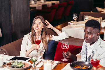 mixed-race couple enjoying an evening meal with red wine at a restaurant.