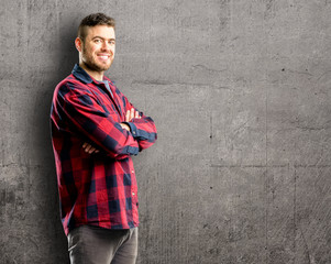 Young handsome man with crossed arms confident and happy with a big natural smile laughing