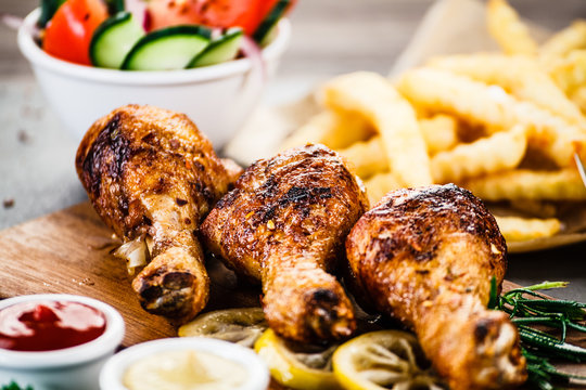 Grilled chicken drumsticks with French fries and vegetables