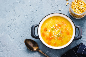 Split pea soup in a pot on blue concrete background. Top view, copy space.