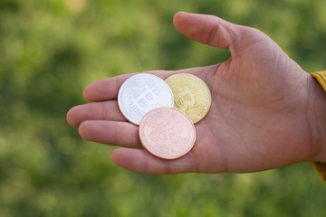 Golden, silver, copper bitcoins in hand