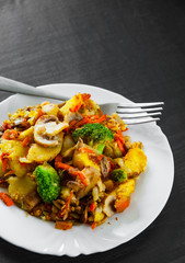 Mixed vegetables and mushrooms in a plate on dark wooden table