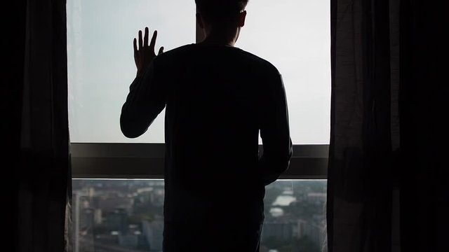 Silhouette of man touching window in slow motion