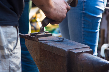 blacksmith performs the forging of hot glowing metal on the anvil