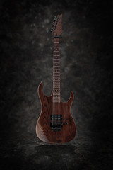 Electric guitar with natural finish isolated on dark grunge background, low key