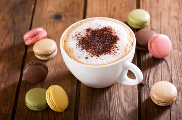 Cup of cappuccino coffee with french macaroons