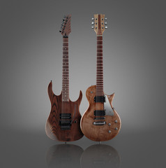 Two different shaped electric guitars with natural finish isolated on grey background with reflection