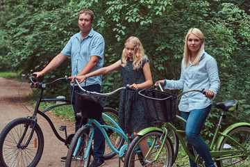 Attractive family dressed in casual clothes on a bicycle ride with their cute little spitz dog.