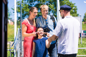 Family buying tickets for river cruise from boatman and entering boat