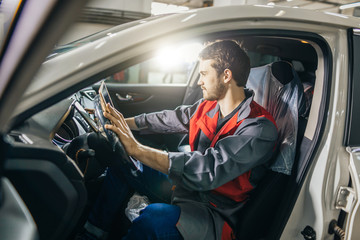 mechanic sitting in car doing diagnostics on digital tablet