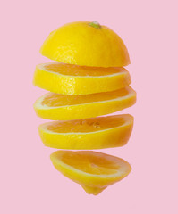 Fototapeta na wymiar Flying lemon. Sliced lemon isolated on gradient pink background. Levity fruit