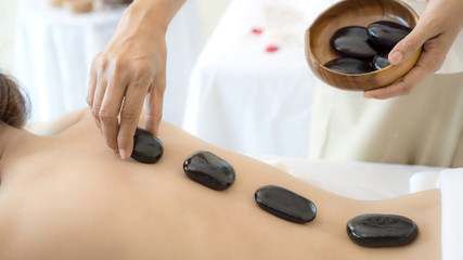 close up beautiful and healthy woman  during a back stone therapy massage in spa salon