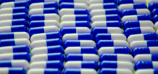 Obraz premium blue and white pills or capsules lies in a rows on blue background close up wallpaper concept design