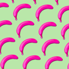 Colorful fruit pattern of pink bananas on green background top view