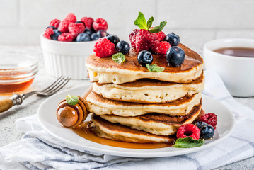 Healthy summer breakfast,homemade classic american pancakes with fresh berry and honey, morning light grey stone background copy space