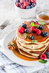 Healthy summer breakfast,homemade classic american pancakes with fresh berry and honey, morning light grey stone background copy space