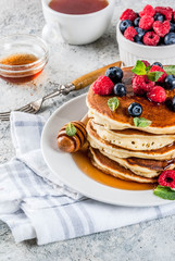 Healthy summer breakfast,homemade classic american pancakes with fresh berry and honey, morning light grey stone background copy space