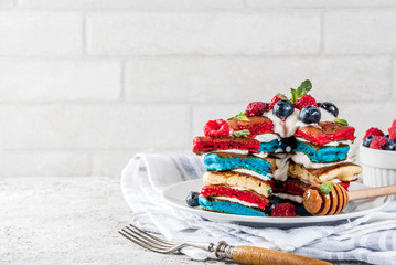 American Independence Day July 4th breakfast idea, homemade white blue red striped pancakes with fresh whipped cream, berry and honey, morning light grey stone background copy space