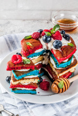 American Independence Day July 4th breakfast idea, homemade white blue red striped pancakes with fresh whipped cream, berry and honey, morning light grey stone background copy space
