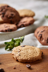 Side view of chocolate chip cookies on a wooden plate over rustic background, selective focus