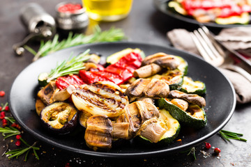 Grilled vegetable salad. Salad of barbecued zucchini, eggplant, sweet pepper, onion and mushrooms on black plate