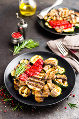 Grilled vegetable salad. Salad of barbecued zucchini, eggplant, sweet pepper, onion and mushrooms on black plate