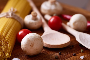 Uncooked pasta, tomatoes and spice on wooden background, top view, close-up, selective focus