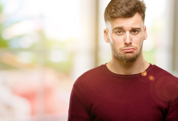 Handsome young man with sad and upset expression, unhappy