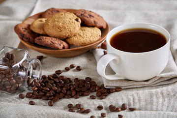 Morning coffee in white cup, chocolate chips cookies on cutting board close-up, selective focus