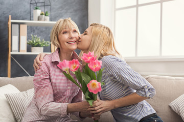 Daughter giving flowers to adult mother