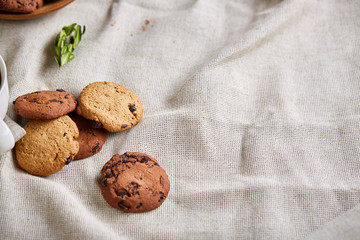 Roasted coffee beans get out of overturned glass jar on homespun tablecloth, selective focus, side view