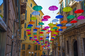 GENOA, ITALY, APRIL 16, 2018 - Multicolored umbrellas in the sky above the streets in the center of Genoa, Italy.