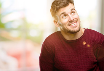 Handsome young man confident and happy with a big natural smile laughing looking up