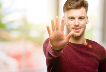 Handsome young man raising his finger, is the number five