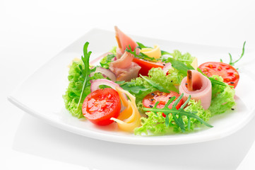 Fresh salad with tomatoes, arugula, cheese and ham on the white plate and white background