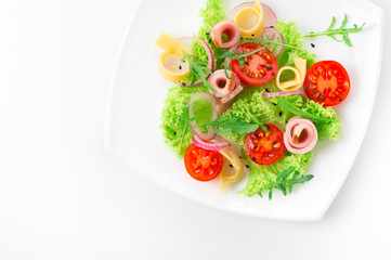 Fresh salad with tomatoes, arugula, cheese and ham on the white plate and white background