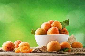 Sweet apricots in bowl on grey wooden table