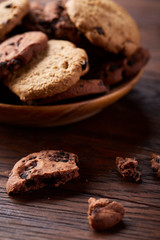 Fototapeta na wymiar Side view of chocolate chip cookies on a wooden plate over rustic background, selective focus