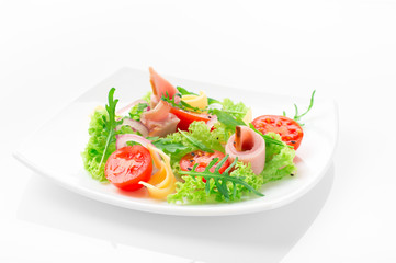 Fresh salad with tomatoes, arugula, cheese and ham on the white plate and white background